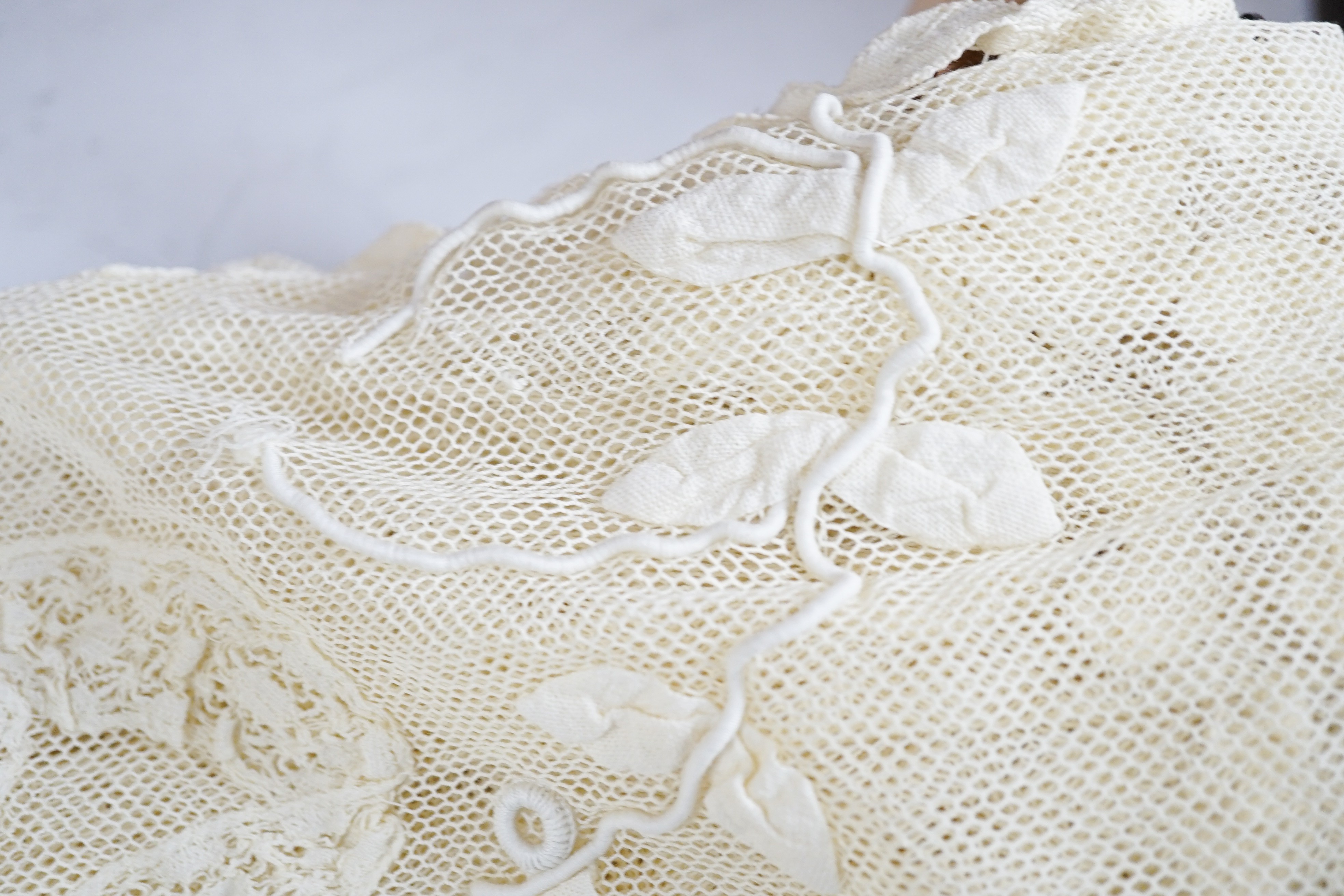 A cream tape vale on net bed cover, approximately 264 x 210cm